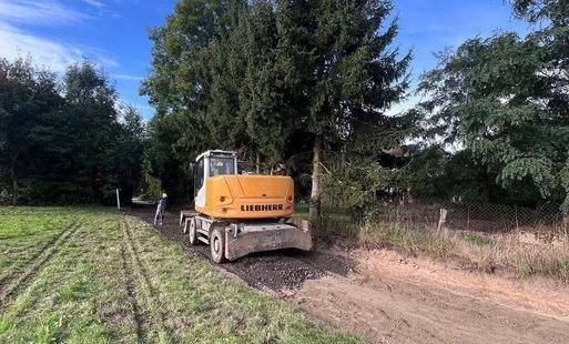 Zdjęcie rpzedstawa koparkę wykonującą prace ziemne przy przebudowie drogi w Pisarzowicach